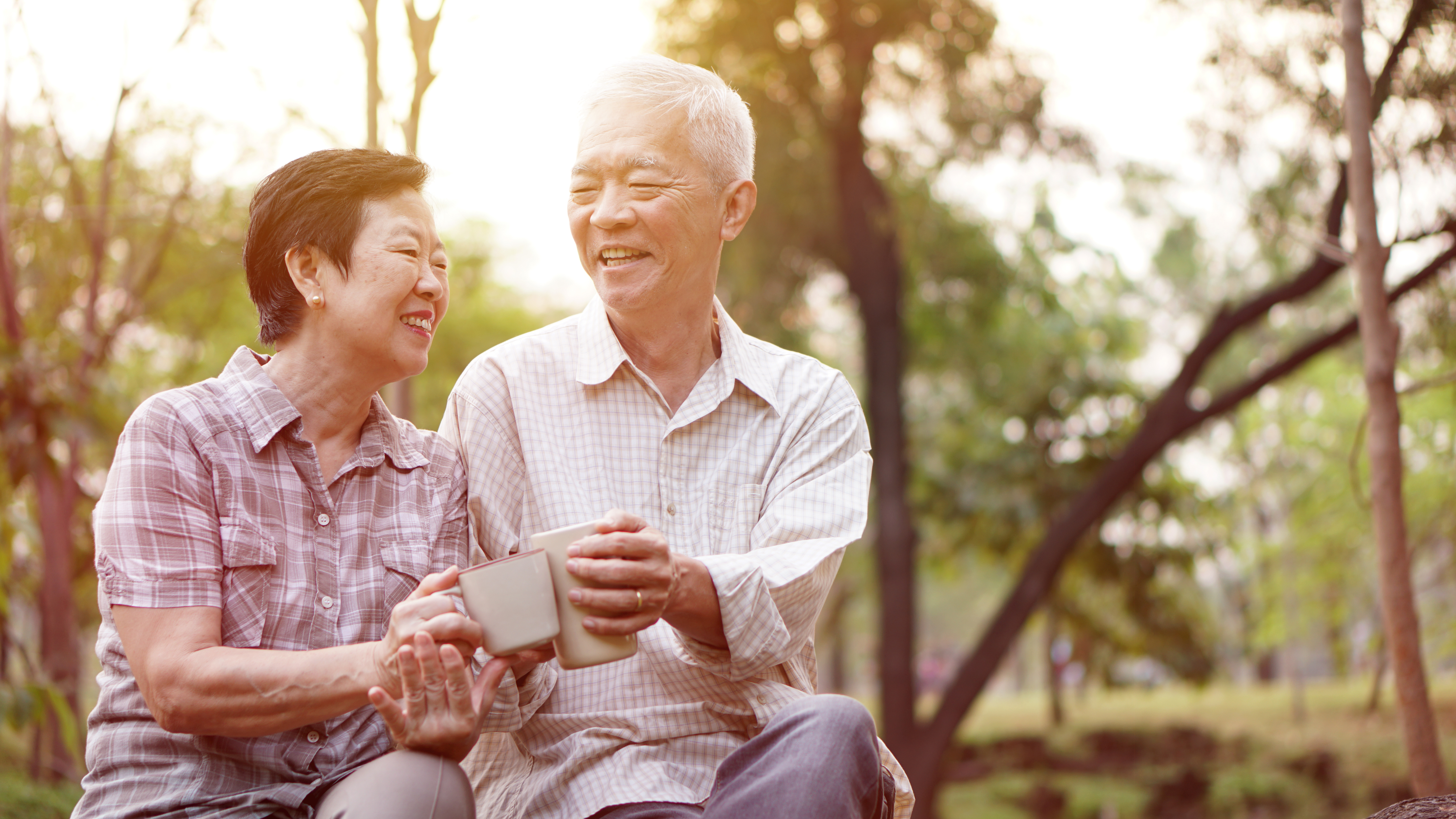 Healthy Asian senior couple drinking coffee in morning park together