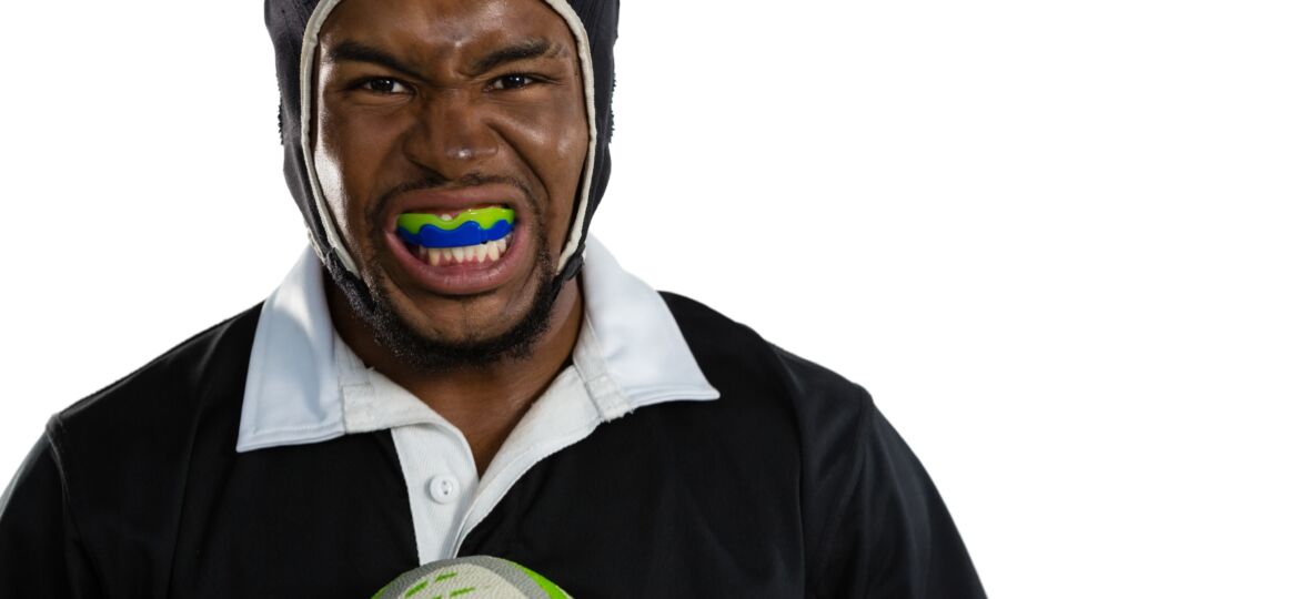 Portrait of male rugby player wearing mouthguard white holding